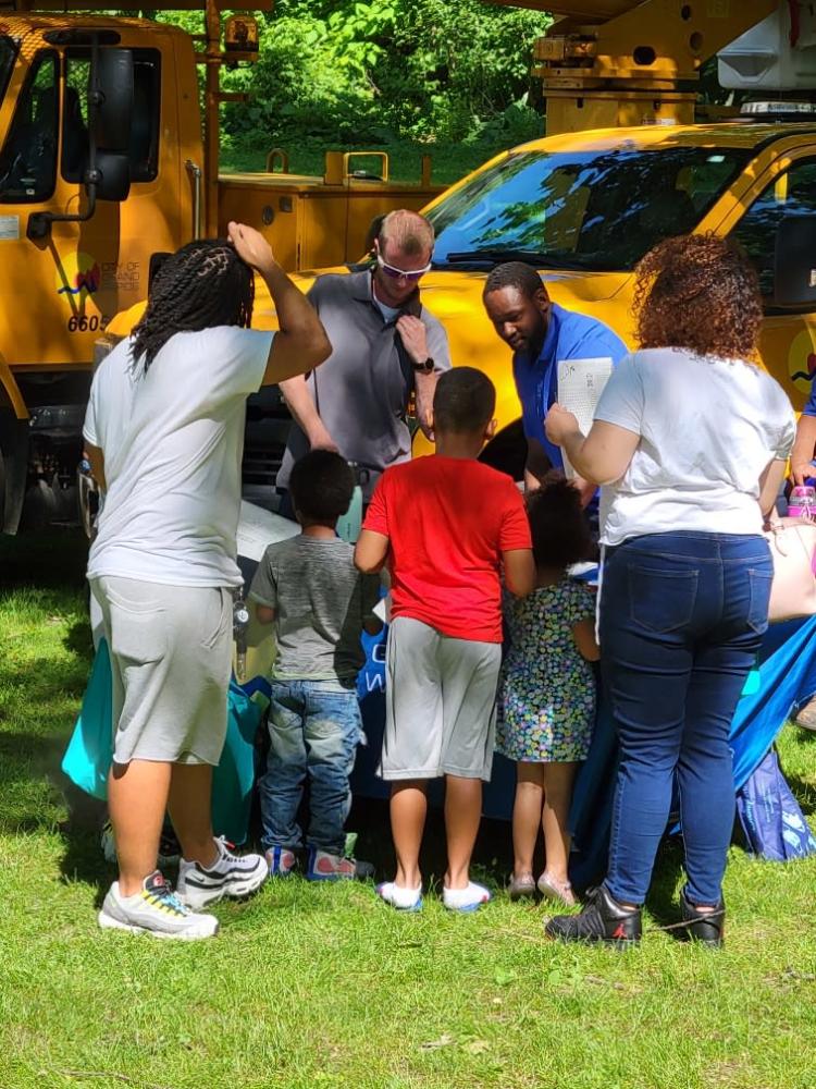 public works staff talking with a group of children and adults