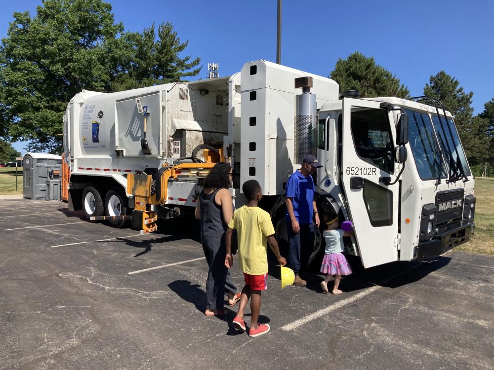 garbage truck with people standing near it