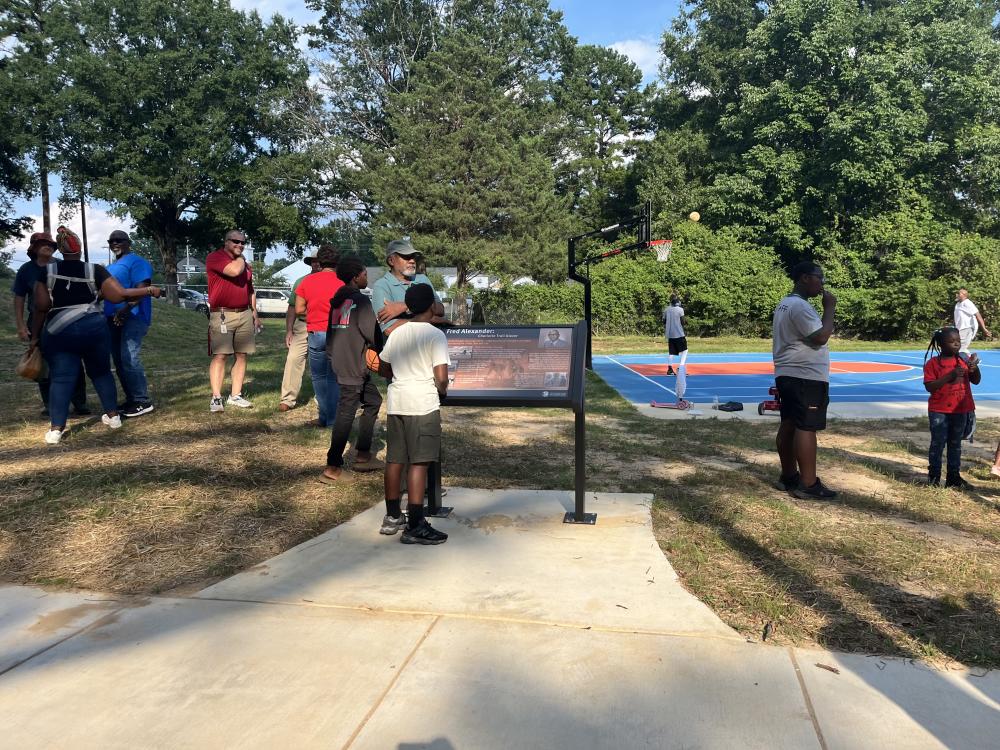 Image of child reading Fred Alexander interpretive sign at park opening.